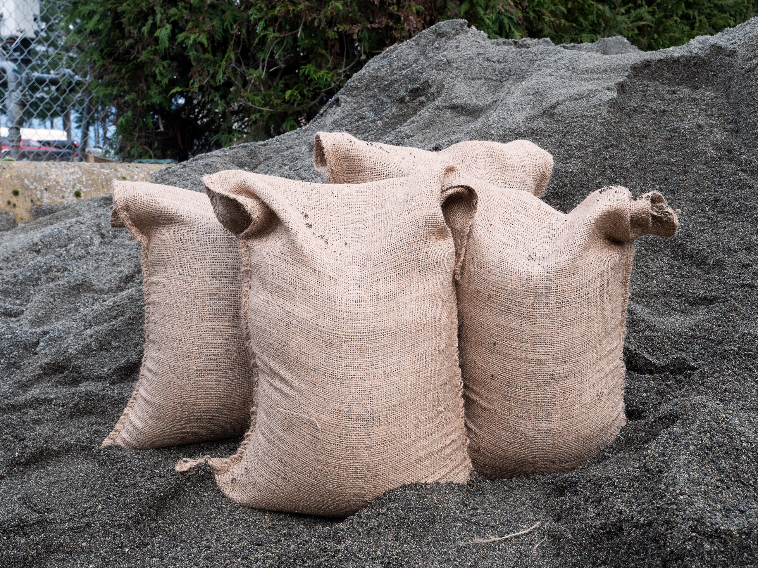 4 sandbags stand filled on a sand pile