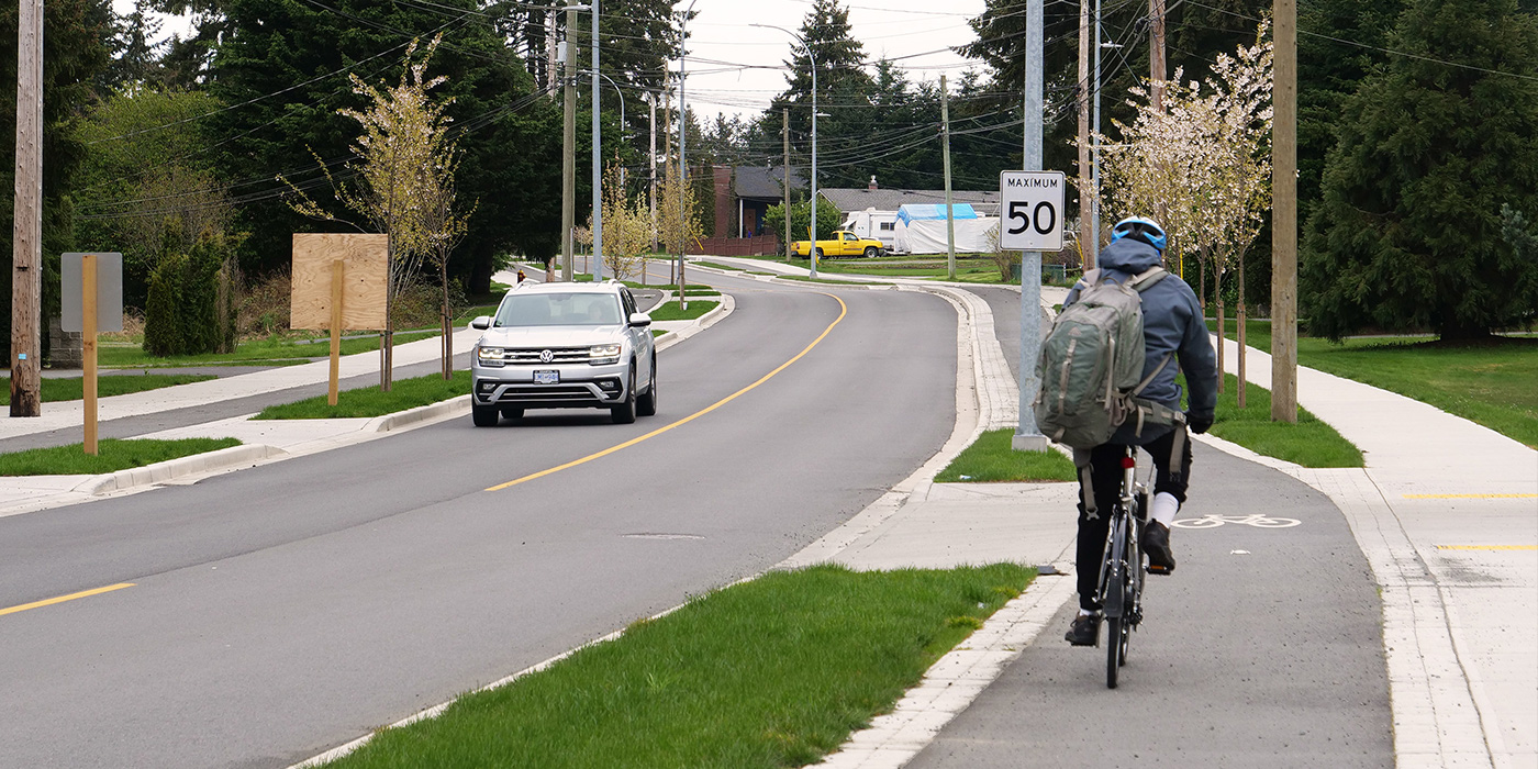 a cyclist rides on a new Metral Drive bike lane while an oncoming car passes