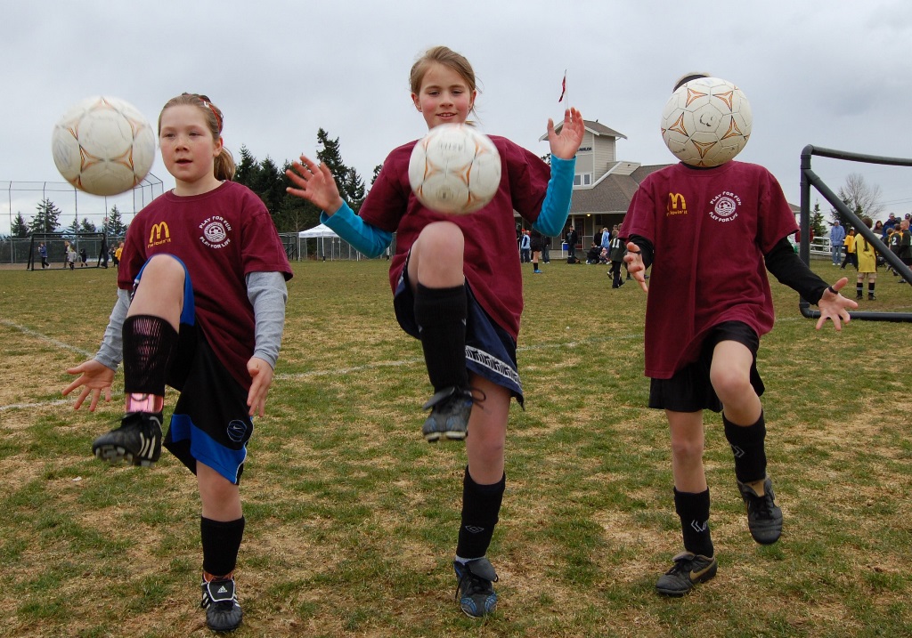 children with soccer balls bouncing them off their knees