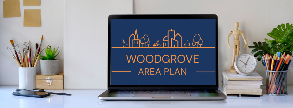 Laptop on a desk displaying the Woodgrove Area Plan with a minimalist cityscape graphic in orange on a dark blue background.