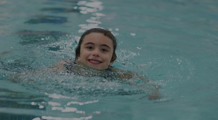 image of child swimming in indoor pool with link to pay view drop-in schedules online