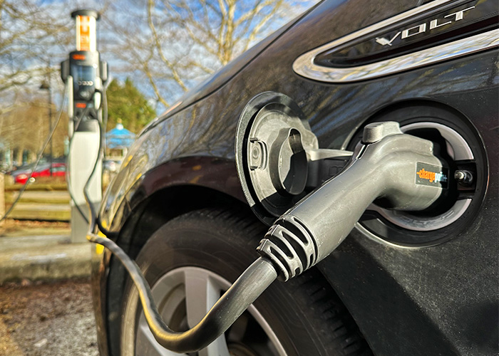 A closeup of a plug charging a PHEV with a chargepoint charger in front of the car.