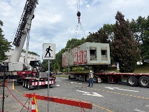 Largemetalboxhungbyacranebeingloadedonaflatdecktruck