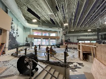 AnemptypoolareawithworkersandalargeconcretesawPlywoodboxesareontheright
