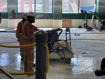 Anemptypoolareawithworkersandalargeconcretesaw