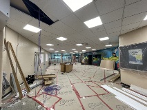AnopenspacewithfloorprotectionandopenceilingtilesThepoolisjustvisibleattheendoftheroomthroughthewindows