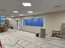 Openlobbyspacewithalargeopeninginthewallattheendandanilluminatedspacebeyondaccessedbyadoorintheleftoftheframe