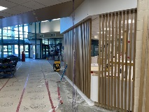 VerticalwoodslatsprovideintermittentvisualseparationtotheguestservicesspacebeyondontherightoftheframeAccessthroughthelobbytotheoutsideisontheleftoftheframe